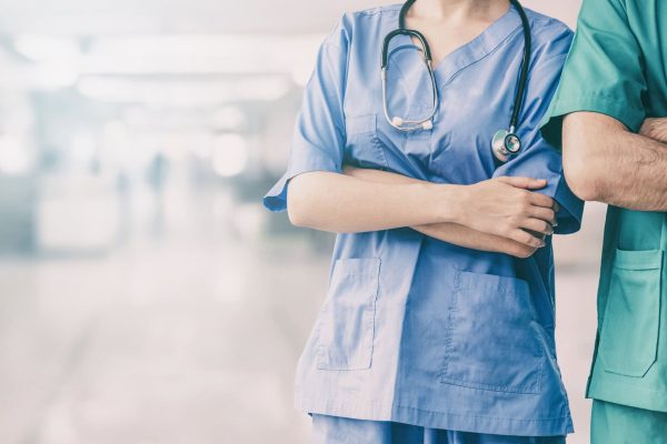Two hospital staffs - surgeon, doctor or nurse standing with arms crossed in the hospital. Medical healthcare and doctor service.